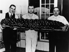 Bakers at Perlmutar’s Bakery hold a 99lb challah prepared for the Hadassah Bazaar, Toronto, 1938. OJA, #4495.  Left to right: Ben Zalvin; Harry Elishevitz; Arrin Perlmutar.