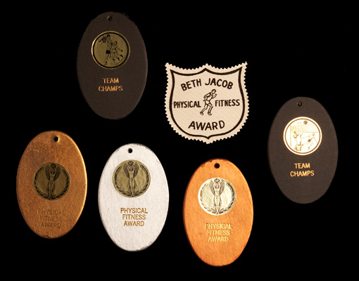 Gold, silver and bronze “medals” and an award badge from the Beth Jacob athletics program, ca. 1965