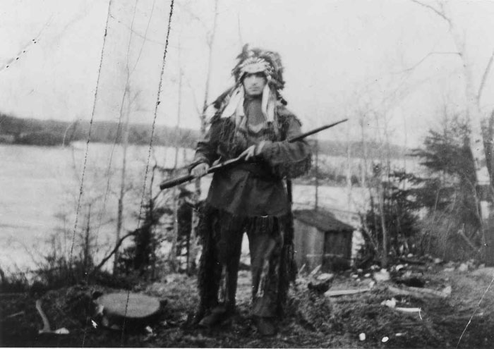 Grey Owl dressed in traditional aboriginal clothing, Biscotasing, 1919