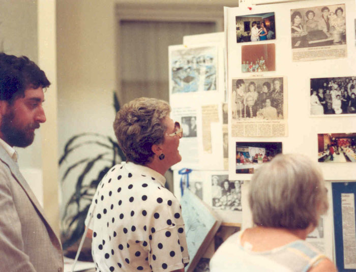 Community members look at photographs and newspaper clippings