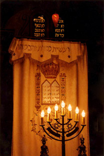 The aron kodesh by candlelight. The embroidered curtain, or parochet, conceals the Torah scrolls, which are housed behind it. 